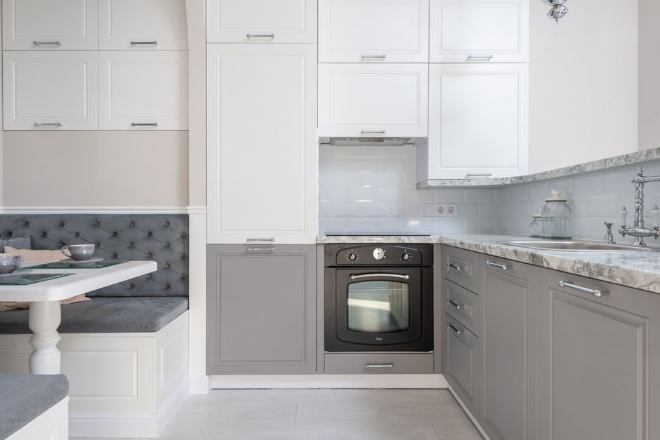 Served table with dishware placed near marble kitchen counter with white and gray cupboards and modern kitchenware in stylish apartment