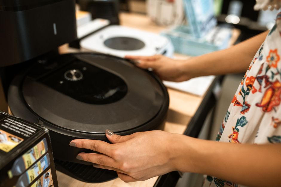 A customer examines a sleek robotic vacuum cleaner in a modern store.