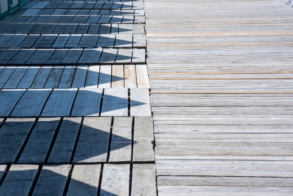 Wooden slats creating geometric shadow patterns on a sunny day.