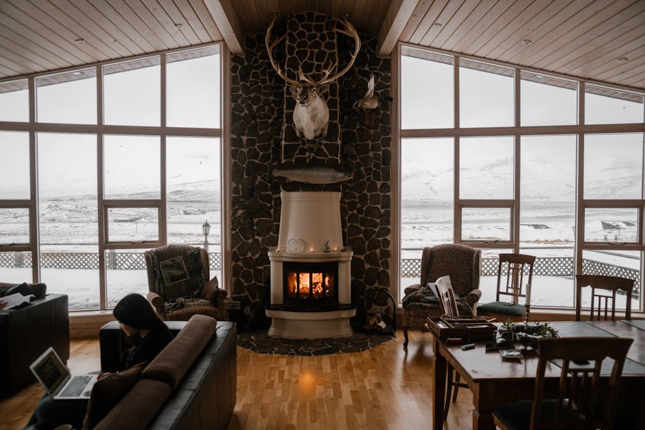 Warm and inviting living room with a fireplace and large windows overlooking snow-covered mountains.