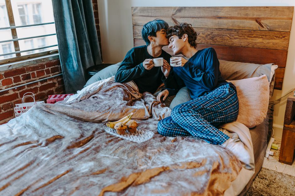 Cozy morning scene with couple sharing coffee and pastries in bed, creating a romantic and loving atmosphere.