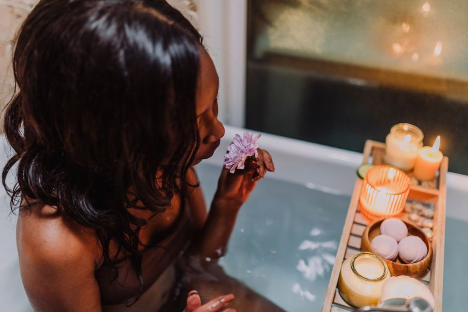 Woman enjoying a relaxing aromatherapy bath with candles and a flower for ultimate relaxation.