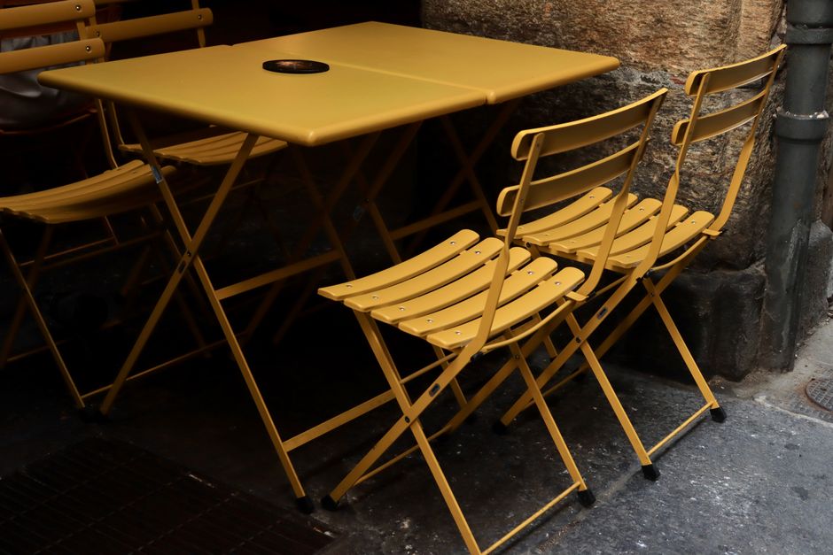 Foldable yellow bistro chairs and table on a Turin street, offering a cozy, urban ambiance.