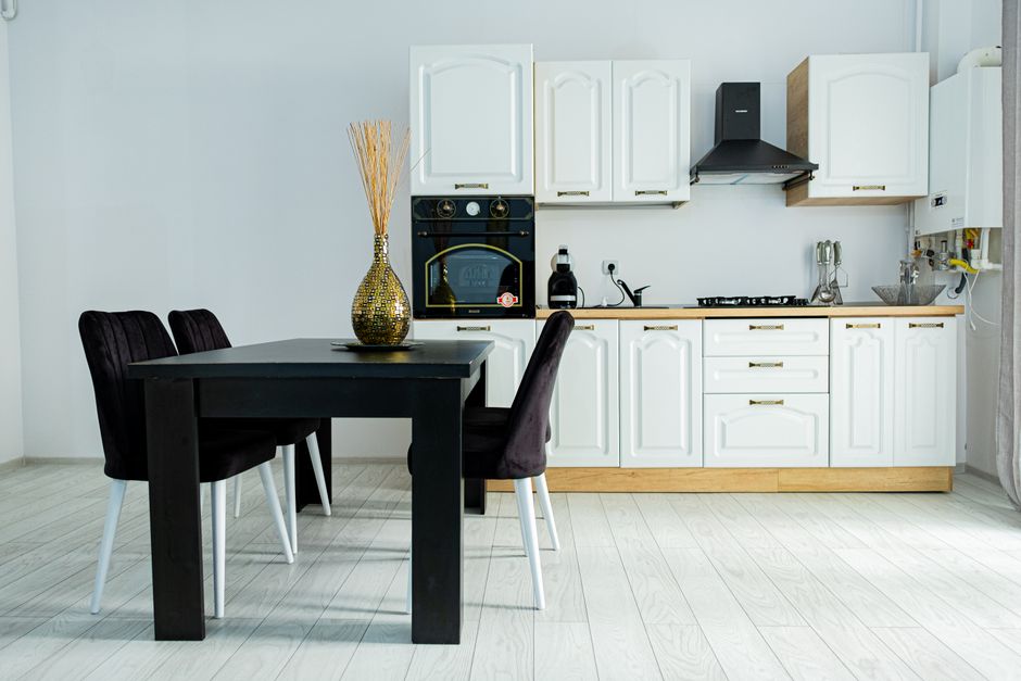 Stylish kitchen interior featuring a black table, chairs, and elegant white cabinetry for a modern look.