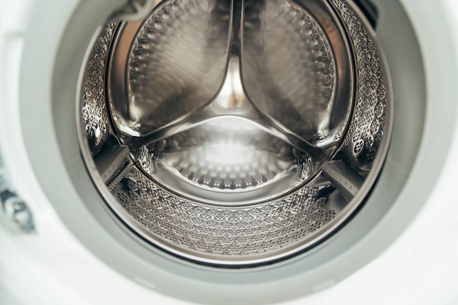 Detailed view of a clean, modern washing machine drum, showcasing shiny stainless steel interior.